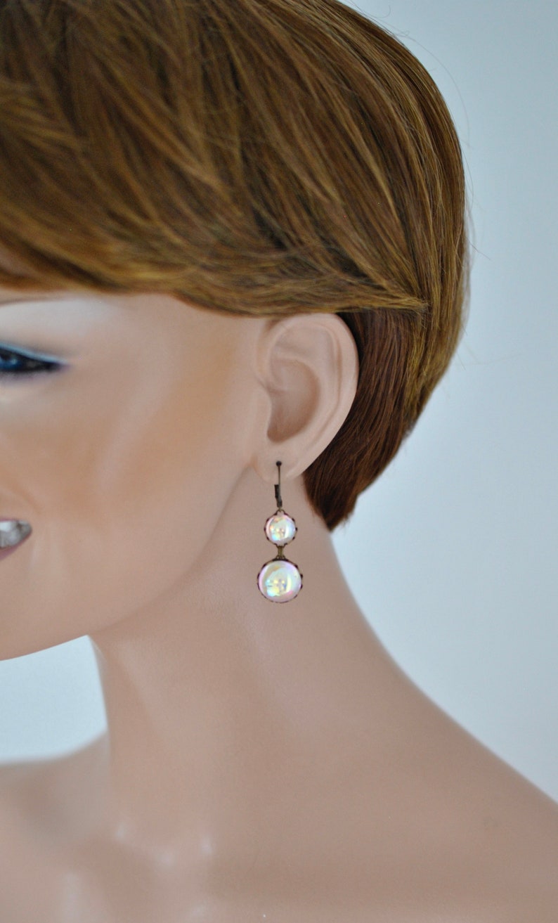 May include: A pair of iridescent pearl drop earrings with a bronze finish.