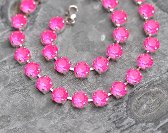 May include: A pink crystal necklace with silver chain links. The necklace is made of round, faceted crystals.