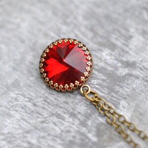 May include: A red gemstone pendant necklace with a detailed ornate bronze setting and a bronze chain.