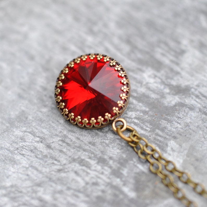May include: A red gemstone pendant necklace with a detailed ornate bronze setting and a bronze chain.