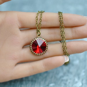 May include: A red crystal pendant necklace with a bronze chain. The pendant is round and has a faceted design.