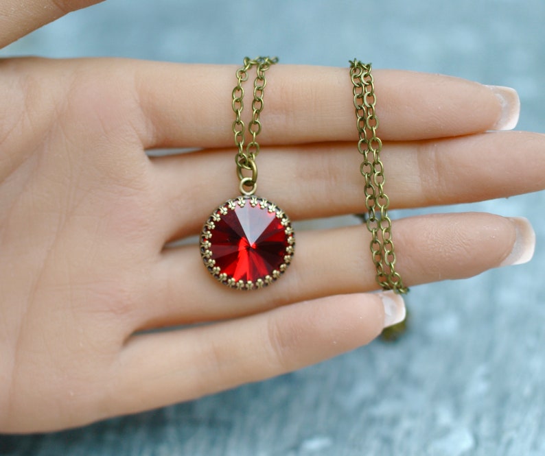May include: A red crystal pendant necklace with a bronze chain. The pendant is round and has a faceted design.