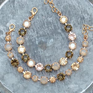 May include: Two gold chain bracelets with alternating crystal beads in shades of brown, beige, and white.