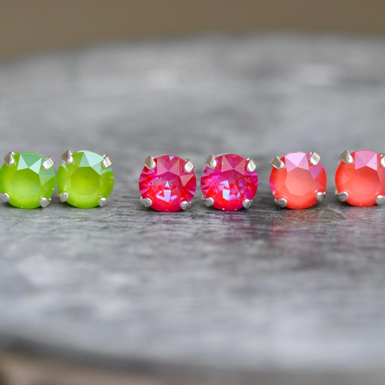 May include: Six small round earrings with silver settings. Two are lime green, two are pink with iridescent shimmer, and two are coral with iridescent shimmer.