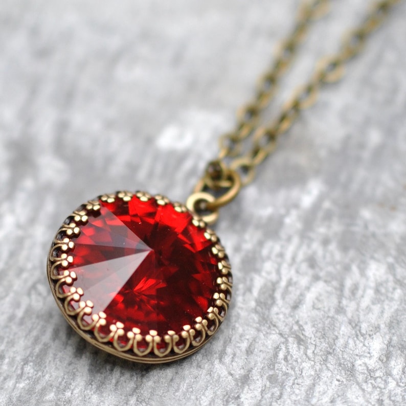 May include: A red gemstone pendant necklace with a gold-toned chain and a decorative filigree border around the stone.