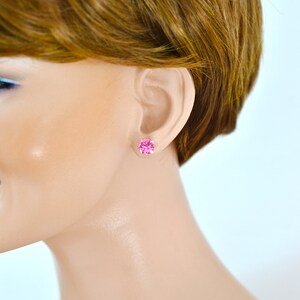May include: A pair of small pink stud earrings with a round, faceted stone.