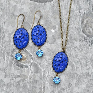 K&ouml;nnte beinhalten: Ein blaues und bronzenes Halsketten- und Ohrring-Set mit floralem Design und blauen Kristall-Akzenten.