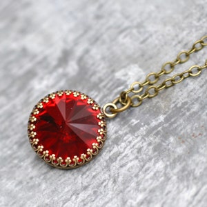 May include: A red crystal pendant necklace with a gold-toned chain and a decorative bezel setting.