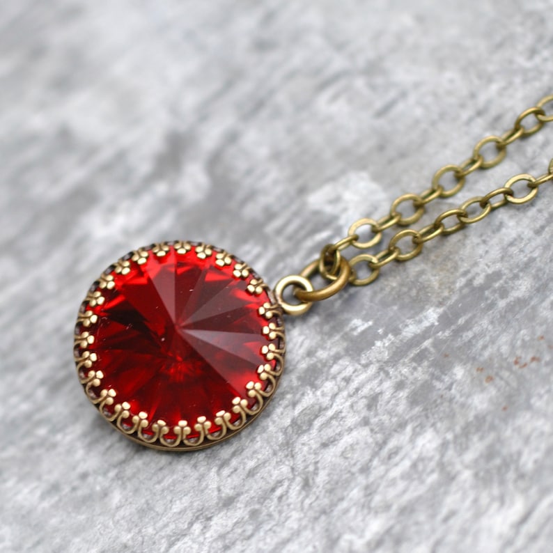 May include: A red crystal pendant necklace with a gold-toned chain and a decorative bezel setting.