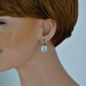 May include: Gold earrings with a square-shaped blue gemstone.
