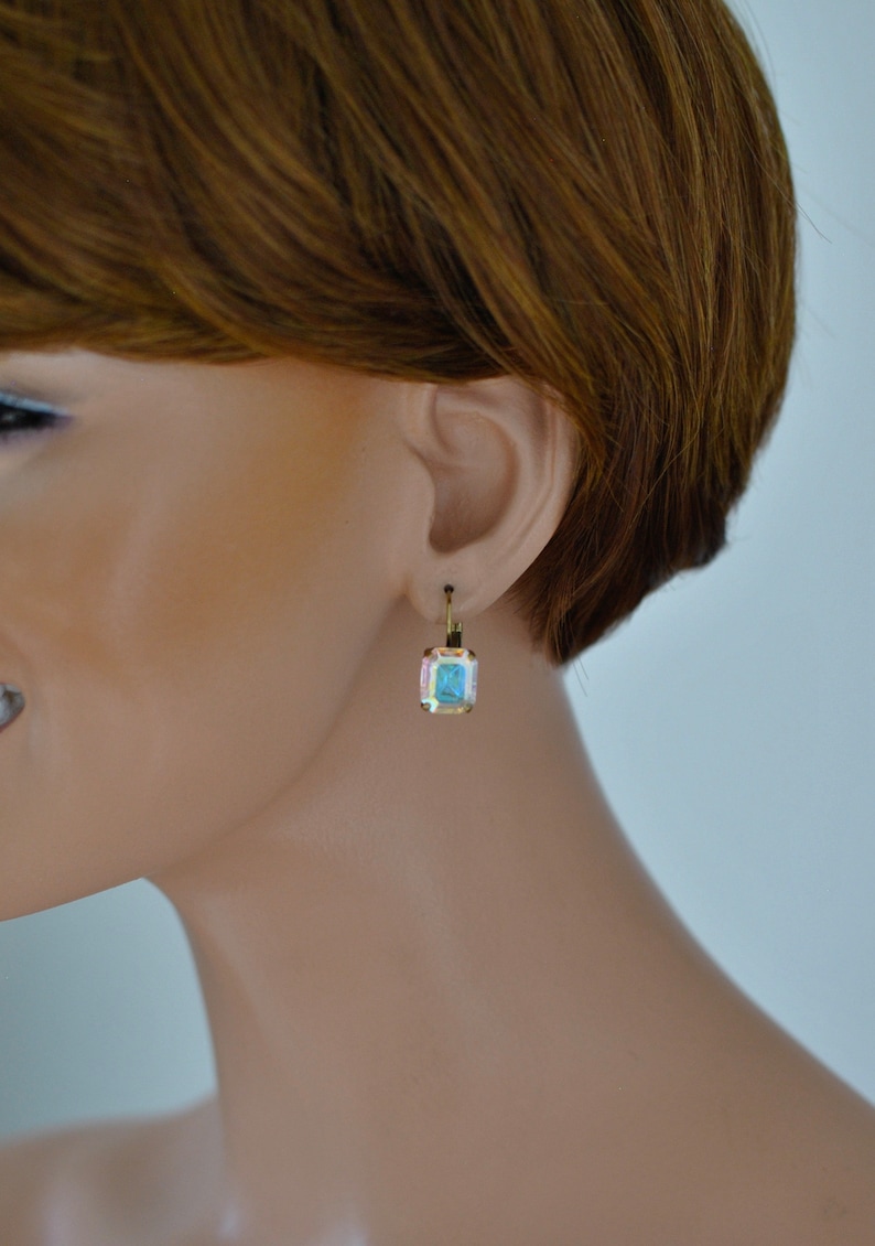 May include: Gold earrings with a square-shaped blue gemstone.