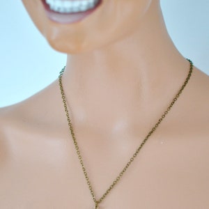 May include: A red gemstone pendant necklace with a bronze chain. The pendant is round and has a faceted design.