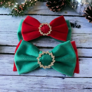 May include: Two velvet bows with jeweled centrepieces. The top bow is red and the bottom bow is green.