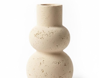 Puede incluir: Un jarrón de cerámica beige texturizado con un diseño apilado único. El jarrón presenta una base redondeada, una esfera en la sección media y una parte superior cilíndrica. El color neutro y la forma orgánica lo convierten en una pieza decorativa versátil.