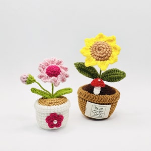Può includere: Due piante in vaso all'uncinetto. Una pianta ha un fiore rosa e l'altra un fiore giallo. I vasi sono marroni e bianchi con un'etichetta che dice "Fatto a mano con amore".