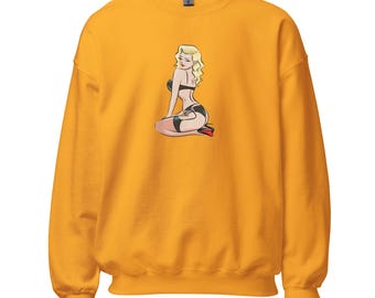 May include: Mustard yellow sweatshirt featuring a retro pin-up girl illustration. The graphic depicts a seated blonde woman in black lingerie and red heels. The sweatshirt has a crew neck and long sleeves.