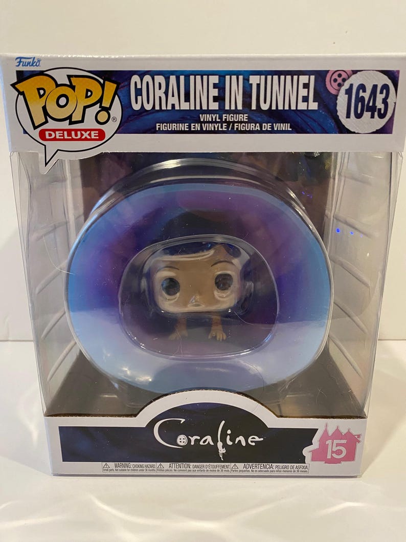 May include: A Funko Pop! Deluxe vinyl figure of Coraline from the movie Coraline. The figure is in a clear plastic box with a purple and blue background. The figure is in a tunnel with a blue and white swirl design. The box has the text "Coraline in Tunnel" and "1643" on it.