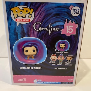 May include: A Pop! Deluxe vinyl figure of Coraline from the movie Coraline. The figure is in a blue and purple tunnel. The box has the text "Pop! Deluxe" and "Coraline 15" on it. The box also has the text "Coraline in Tunnel" and "Collect Them All!" on it.