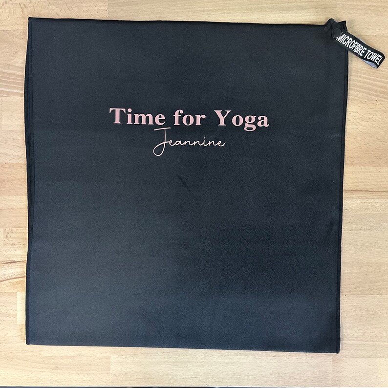 Pu&ograve; includere: Asciugamano da yoga nero con il testo "Time for Yoga" e il nome "Jeannine" scritto in rosa.