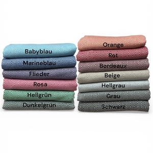 May include: Stacks of folded blankets in various colors, including blue, pink, green, and orange. Each blanket features a diamond pattern and a label indicating its color name. The blankets are neatly arranged, showcasing a range of hues.