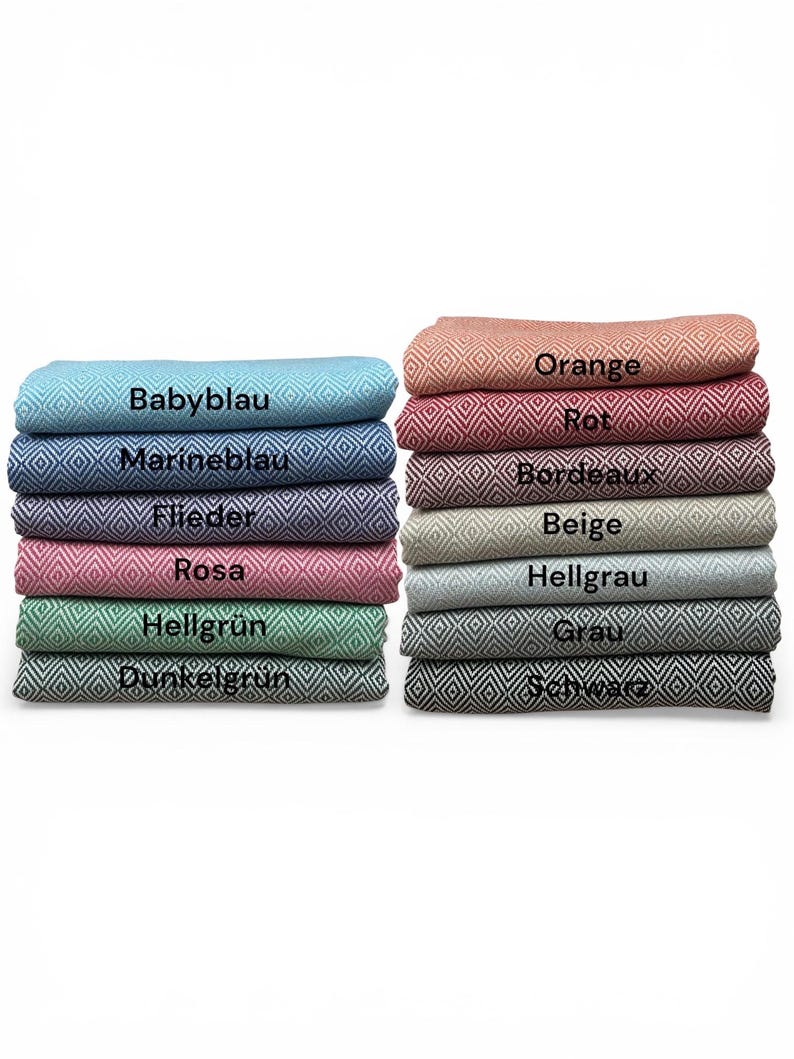 May include: Stacks of folded blankets in various colors, including blue, pink, green, and orange. Each blanket features a diamond pattern and a label indicating its color name. The blankets are neatly arranged, showcasing a range of hues.