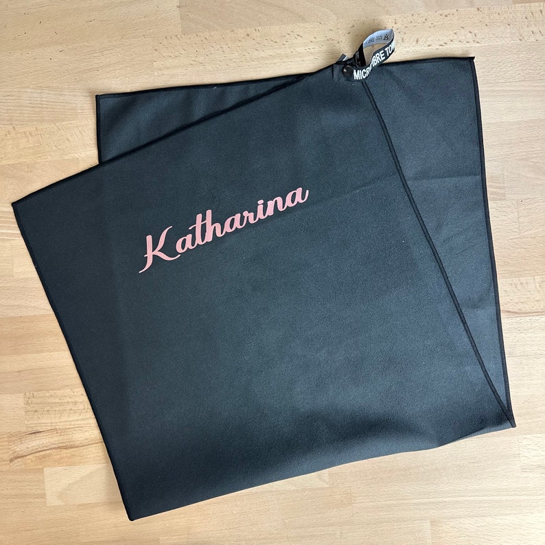Pu&ograve; includere: Asciugamano in microfibra nero con il nome "Katharina" ricamato in lettere rosa.
