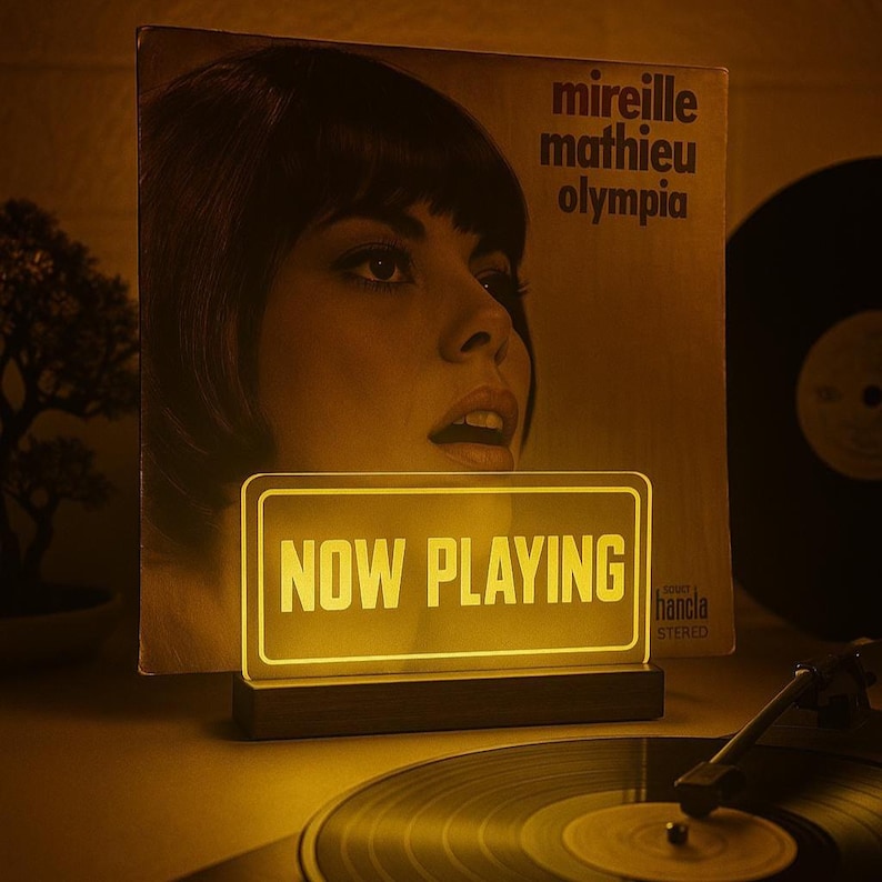 May include: A yellow illuminated sign with the text "NOW PLAYING" on a wooden base in front of a vintage vinyl record with a woman on the cover. The record is titled "Mireille Mathieu Olympia".Valentine's Day Gift, Boyfriend Gift
