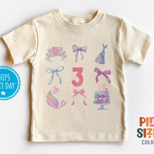 May include: A light beige t-shirt with a pink number 3 and watercolor illustrations of a mermaid, a crown, bows, a party hat, and a birthday cake. The text "Pint Sized Colors" is in the bottom right corner.