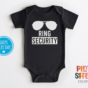 May include: Black baby bodysuit with white text that reads "Ring Security" and a pair of sunglasses.