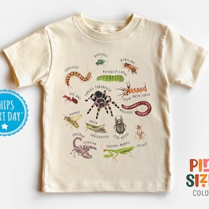 May include: Cream-colored t-shirt featuring colorful illustrations of various insects, including a centipede, tarantula, and grasshopper, with their names printed below. The shirt also has the text "Pint Sized Colors".