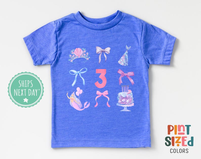 May include: A blue t-shirt with a pink number three and various pink and white illustrations of a mermaid, a crown, bows, and a birthday cake. The text "Ships Next Day" is in the top left corner.