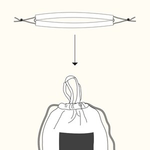 May include: A white drawstring bag with a black rectangular patch on the front. The bag is closed by pulling on the drawstrings, which are visible at the top of the bag.
