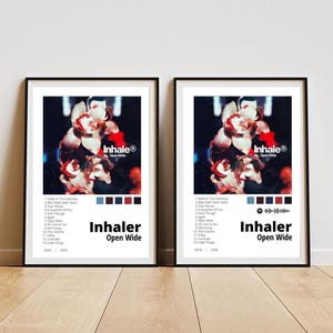 May include: Two framed posters featuring the album art for "Inhaler Open Wide." The artwork includes a floral image with red and white flowers. The album title and tracklist are displayed in a minimalist design with a color palette of blue, burgundy, and white.
