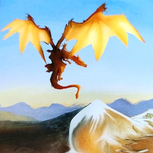 May include: A fantasy art print featuring a dragon with golden wings soaring above a mountain range. The dragon is brown with outstretched wings against a blue sky. The mountain is white and brown.
