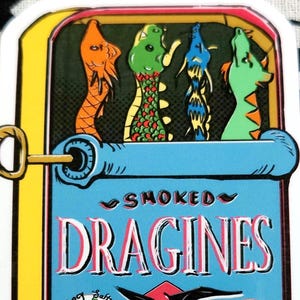 May include: A whimsical illustration of a sardine can labeled "SMOKED DRAGINES." The can features colorful dragon illustrations and text that reads "Fancy, Salty, Breathes Fire" and "packed in their own juices!"