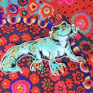 May include: A blue and green cartoon lizard with a whimsical expression, set against a colorful floral background.