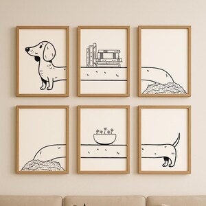 May include: A set of six framed art prints with simple black and white drawings. The prints depict a dachshund, books, a bowl of flowers, and abstract forms. The frames are light brown, and the background is off-white.
