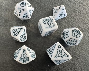 May include: White polyhedral dice with black illustrations of Christmas ornaments, bells, snowmen, and a Santa face. The dice are for tabletop games and feature numbers and holiday-themed images.