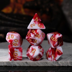 May include: Set of seven red and white marbled dice with gold numbers. The dice are a d4, d6, d8, d10, d%, d12, and d20.