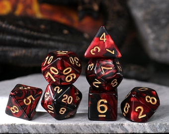 May include: Set of seven black and red dice with gold numbers. The dice are made of a marbled plastic material. The dice are arranged in a pyramid shape.