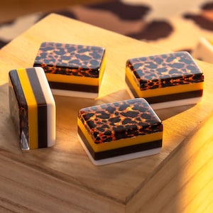 Puede incluir: Tres bloques rectangulares con un diseño en capas que presenta una sección superior con estampado de leopardo marrón y negro, una sección central de color amarillo sólido y una sección inferior de color blanco sólido.
