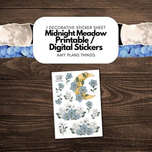 以下が含まれることがあります： 「Midnight Meadow Printable / Digital Stickers」のテキストと花の模様が入った装飾ステッカーシート。ステッカーシートには三日月と青い花が描かれています。背景は濃い木材の表面です。
