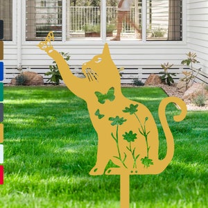 May include: A gold metal cat silhouette garden stake with a butterfly design. The cat is surrounded by flowers and butterflies. The stake is placed in a grassy lawn.