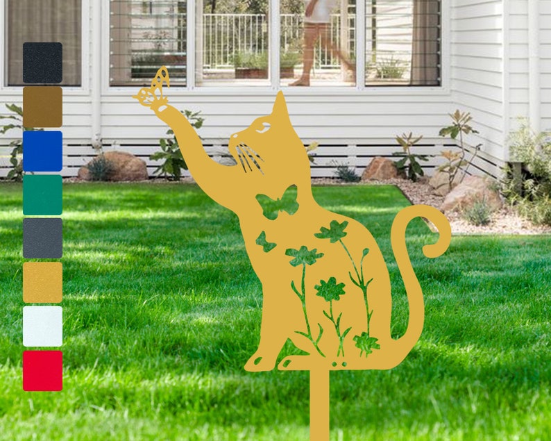 May include: A gold metal cat silhouette garden stake with a butterfly design. The cat is surrounded by flowers and butterflies. The stake is placed in a grassy lawn.