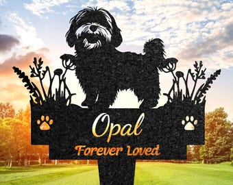 May include: Black metal garden stake featuring a silhouette of a dog, with the name "Opal" and the phrase "Forever Loved". Includes paw print accents and floral details. Set against a green lawn and sky.