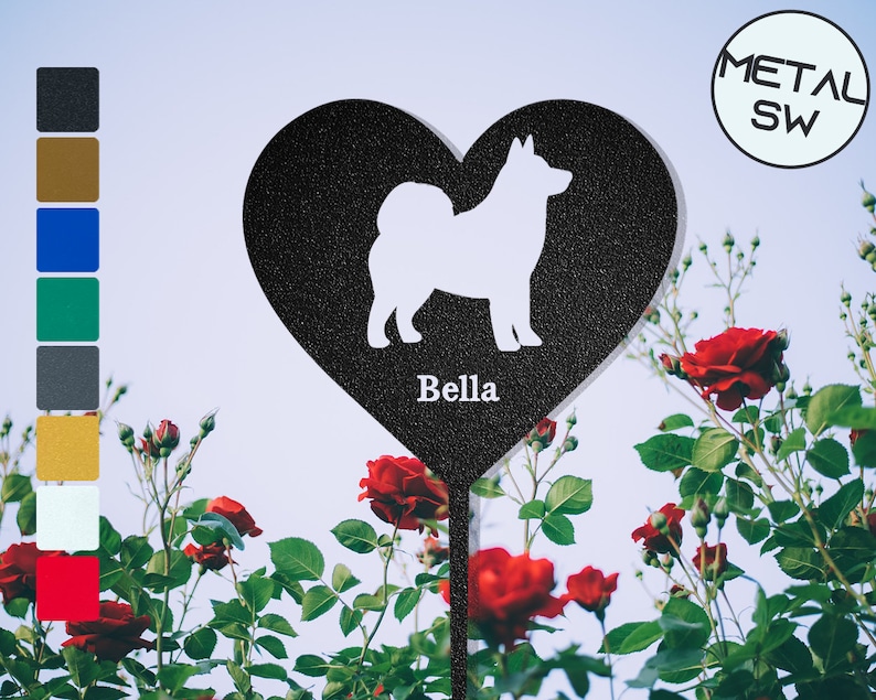 Puede incluir: Estaca de jard&iacute;n de metal negro en forma de coraz&oacute;n con una silueta blanca de un perro dentro del coraz&oacute;n. La estaca tiene el nombre "Bella" escrito debajo del perro. La estaca est&aacute; delante de un arbusto de rosas rojas.
