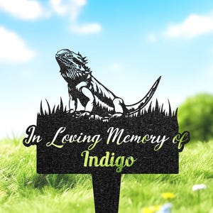 May include: Black metal garden memorial with a silhouette of a bearded dragon lizard and the text "In Loving Memory of Indigo".