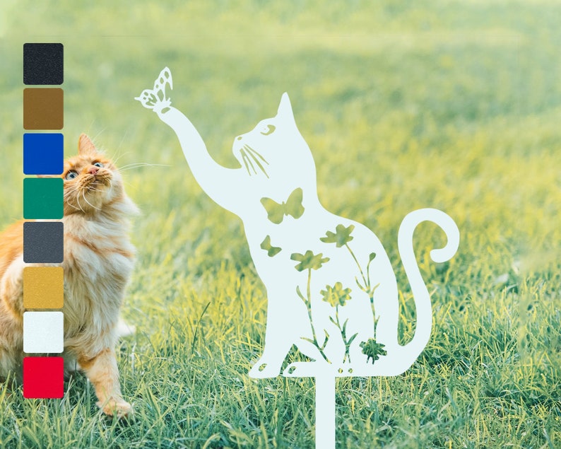 May include: White metal silhouette of a cat reaching up to a butterfly. The cat is decorated with flowers and butterflies. The silhouette is on a green grass background.