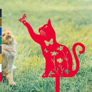 May include: Red metal cat silhouette garden stake with a butterfly and flowers cutouts. The cat is reaching up with its paw as if to catch the butterfly.