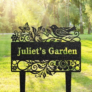 May include: Black metal garden sign with a floral design, a bird, and a butterfly. The sign reads "Juliet's Garden".